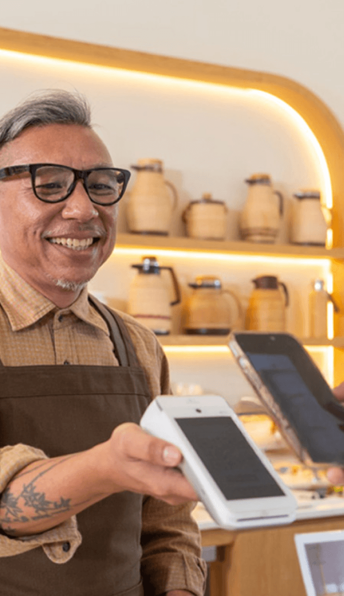 Lojista sorrindo enquanto segura uma máquina de cartão